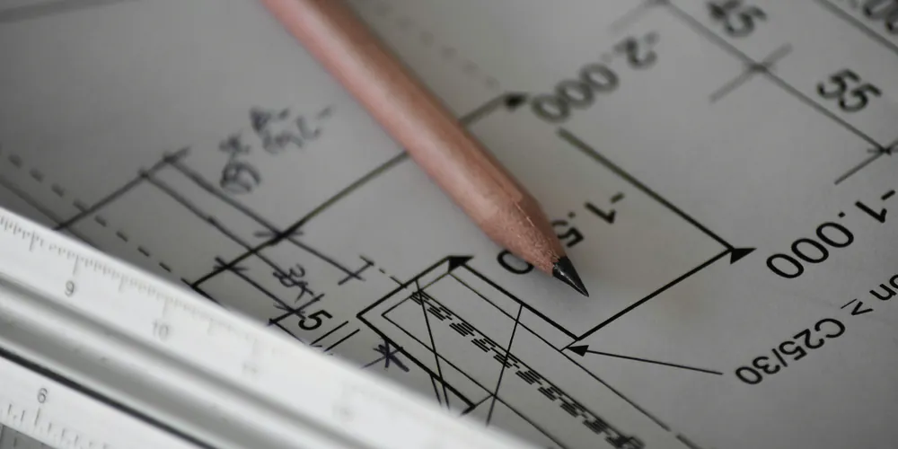 A pencil and a scale ruler over a technical drawing