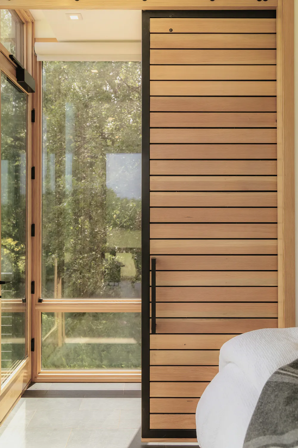 A cedar clad sliding door beside floor to ceiling glass