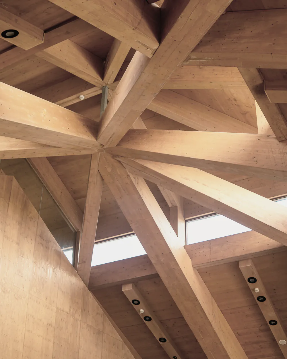Exposed timber roof beams meeting around a skylight