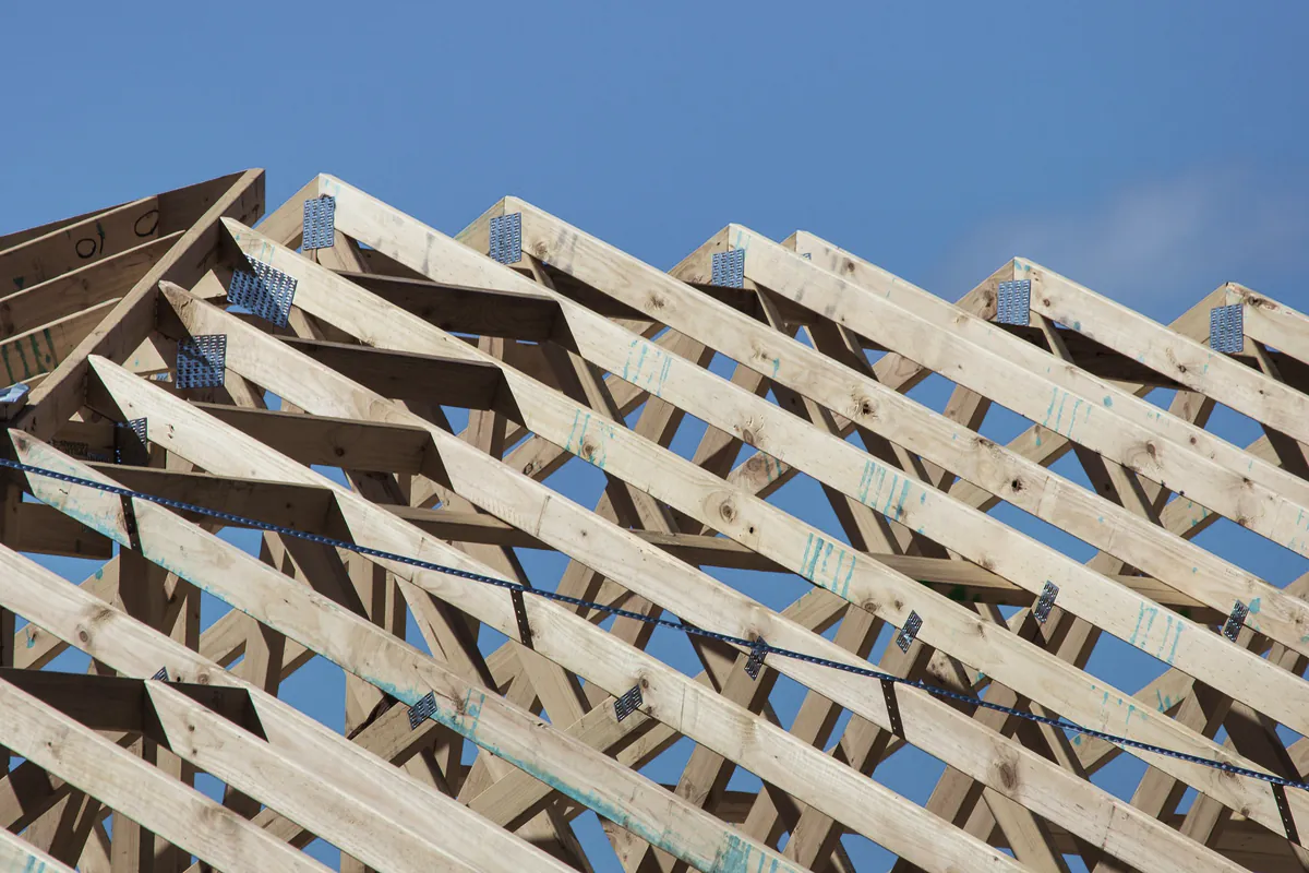 Rows of timber roof trusses against a blue sky
