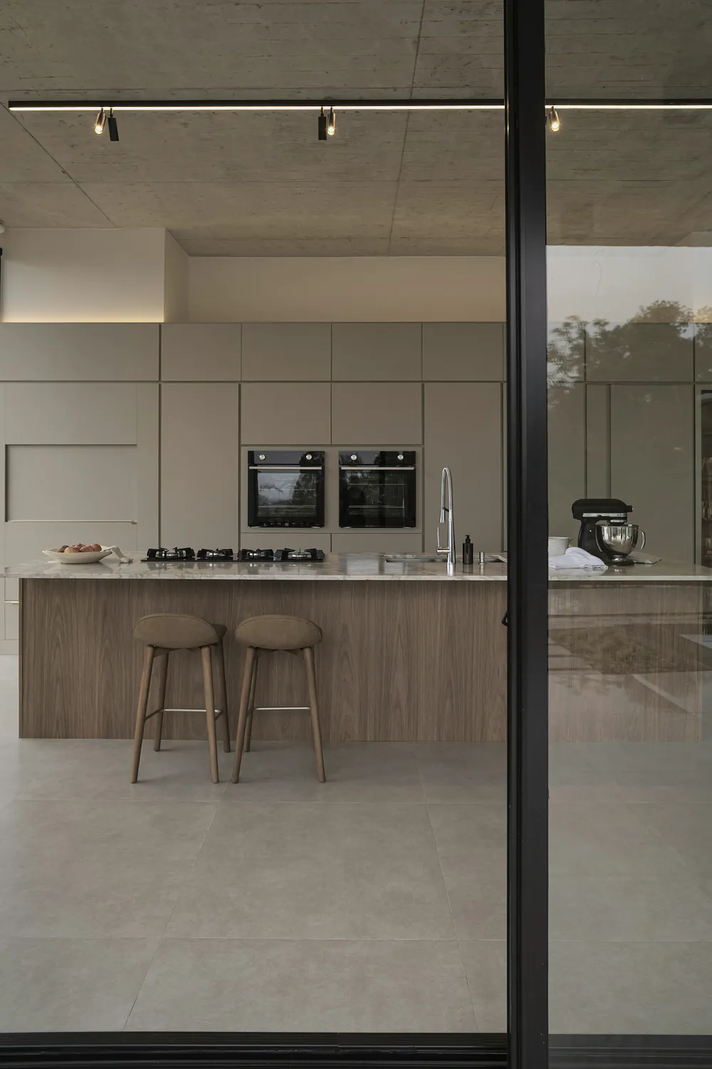 The oak island and pale joinery seen from the terrace through an open glass slider