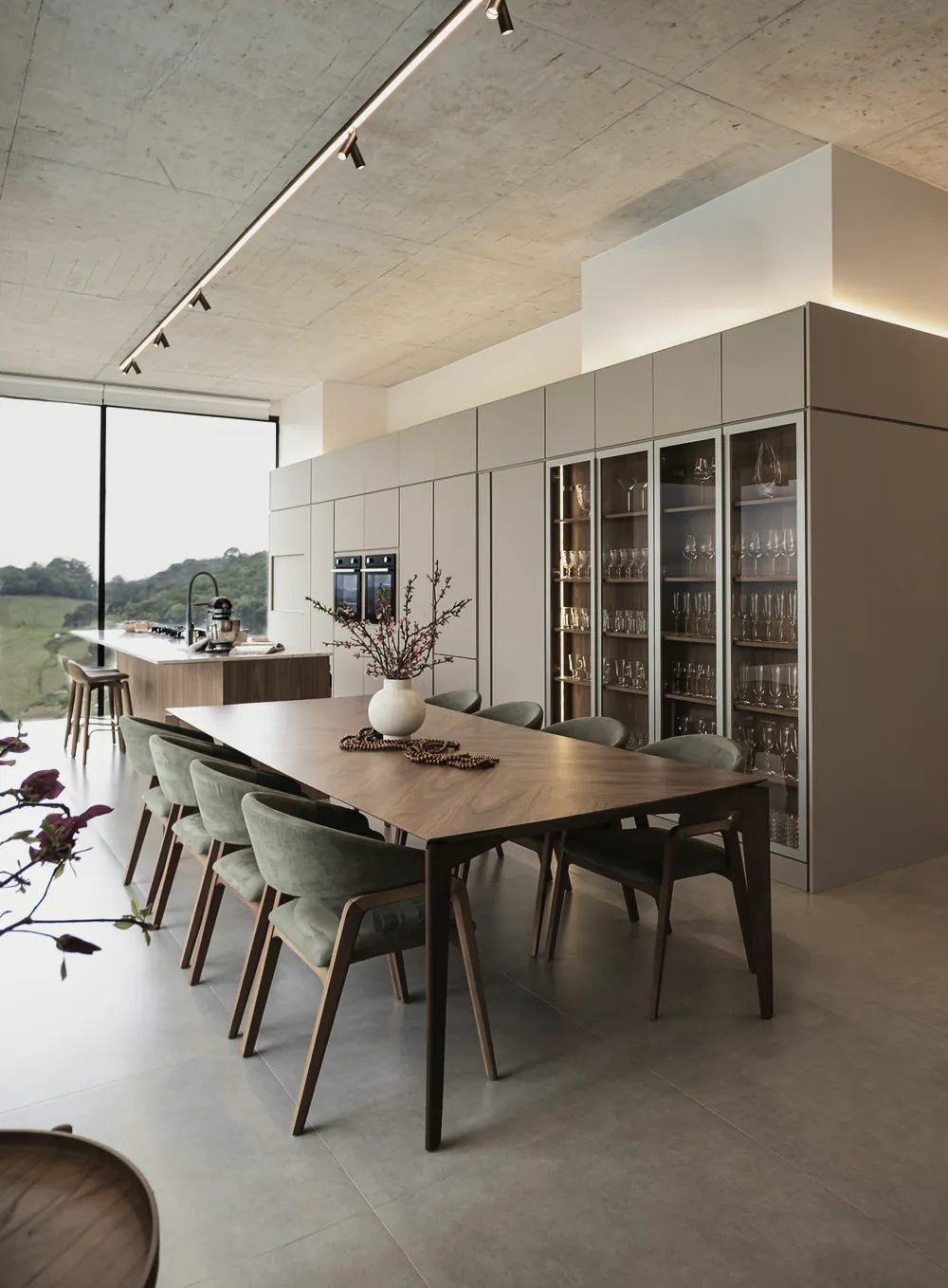 A kitchen with a long island and a dining table under a board formed concrete ceiling
