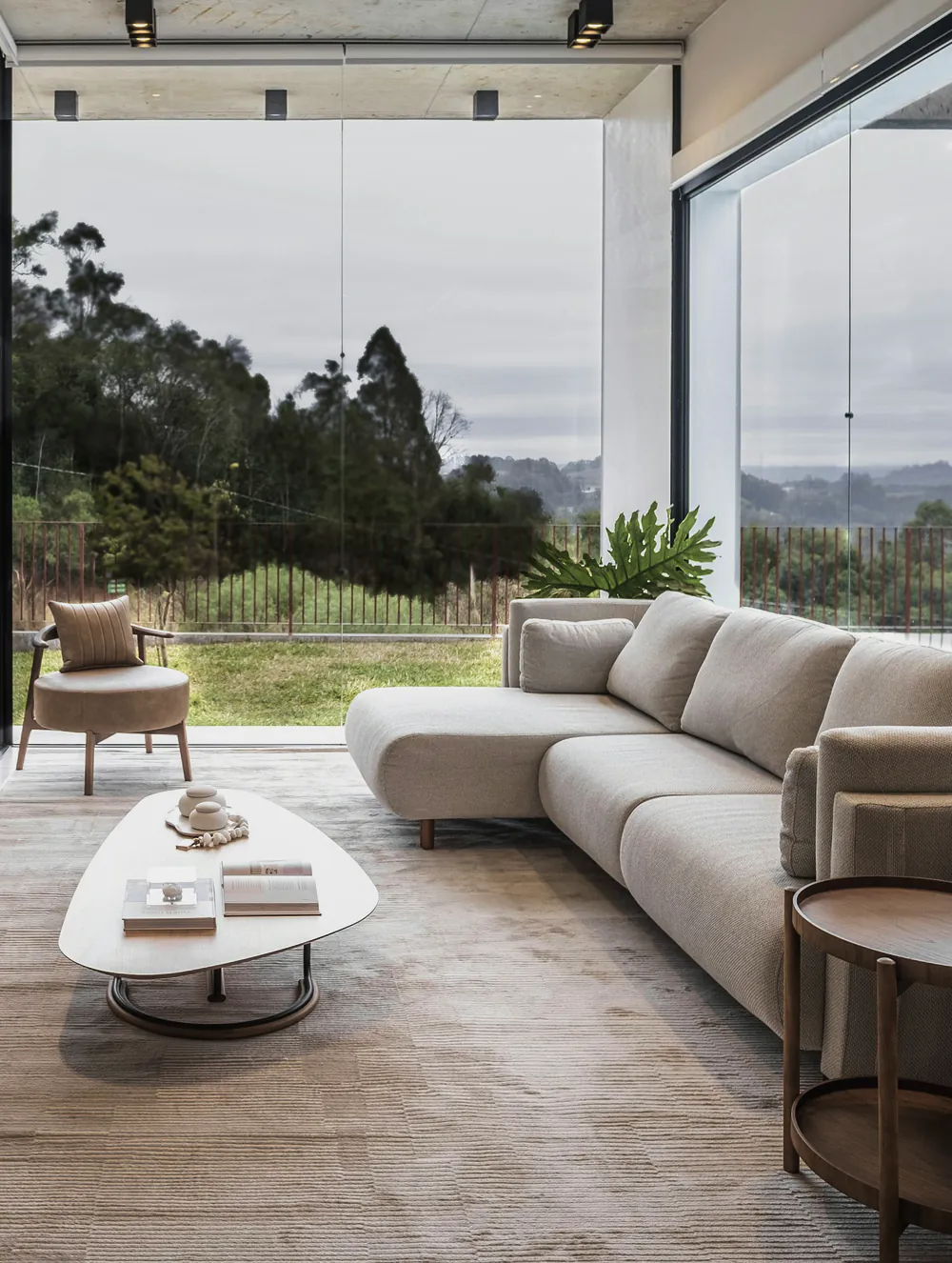 A living room under a board formed concrete ceiling, with a glass wall to the valley
