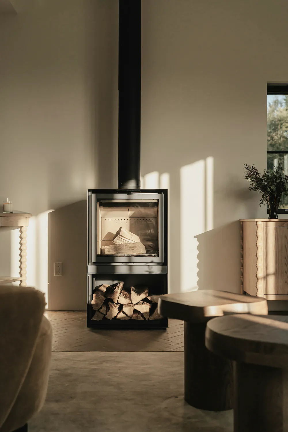 A freestanding wood heater with stacked logs in a living room