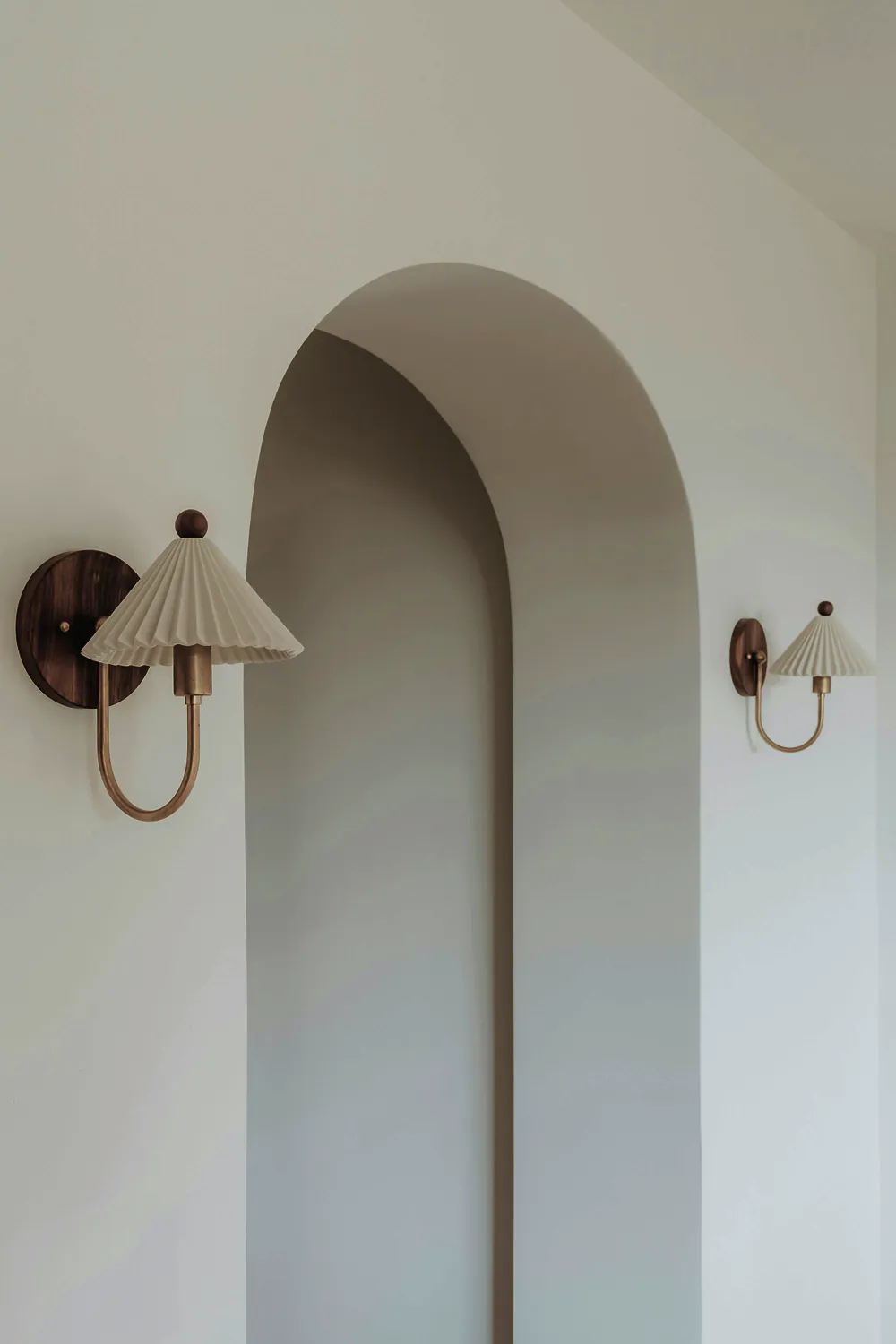 A curved plaster wall between two pleated wall lights